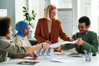 Happy mature teacher passing papers with grammar test or authentic materials