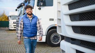 Young man truck driver walking near semi trucks