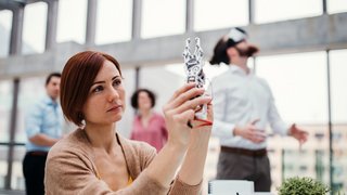 Young businesswoman or scientist with robotic hand standing in office, working.