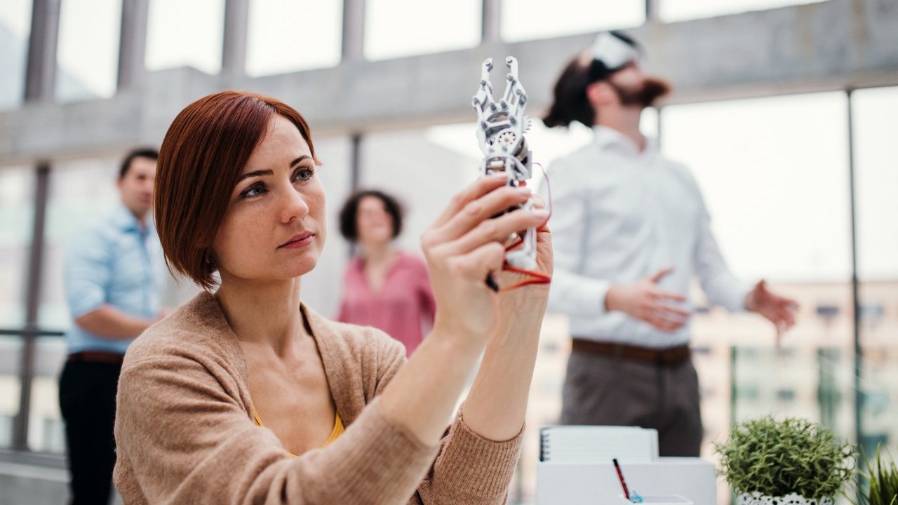 Young businesswoman or scientist with robotic hand standing in office, working.