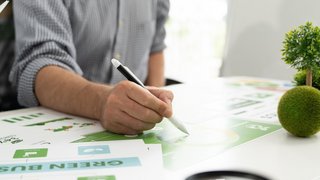 Ein vielfältiges Geschäftsteam analysiert in einer gemeinsamen Besprechung Umweltdiagramme und -grafiken, um in einem modernen Büro nachhaltige Strategien zu entwickeln.