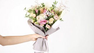 Female hand holding beautiful flower bouquet on white background