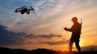 Silhouette of soldier are using drone and laptop computer for scouting during military operation.