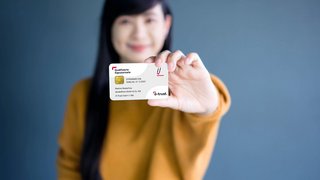 Frau hält eine "Qualifizierte Signatur"-Karte von d-trust nach vorne