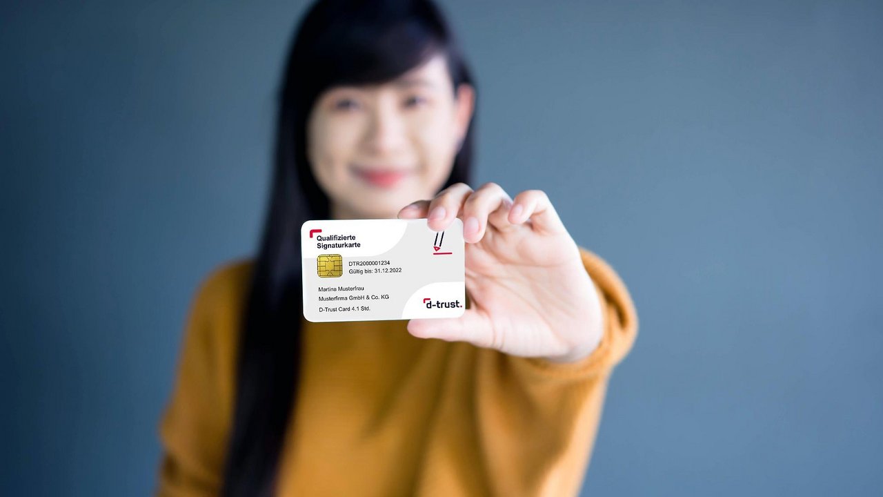 Frau hält eine "Qualifizierte Signatur"-Karte von d-trust nach vorne