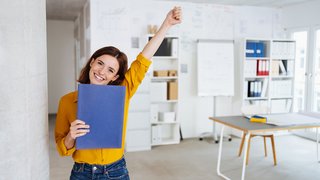 Young student stands in the office with her application documents and is happy about the new job