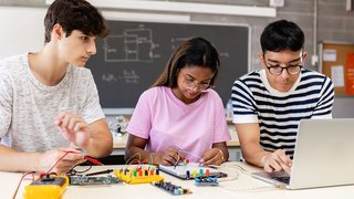 Diverse young teenage student friends learning together at technology class