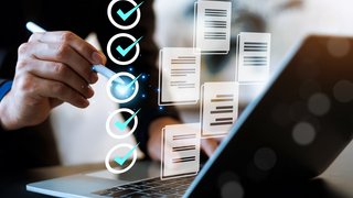 Professional businessman using a laptop with digital checklist and document icons. This conceptual image represents task management, quality assurance, workflow automation, paperless office.