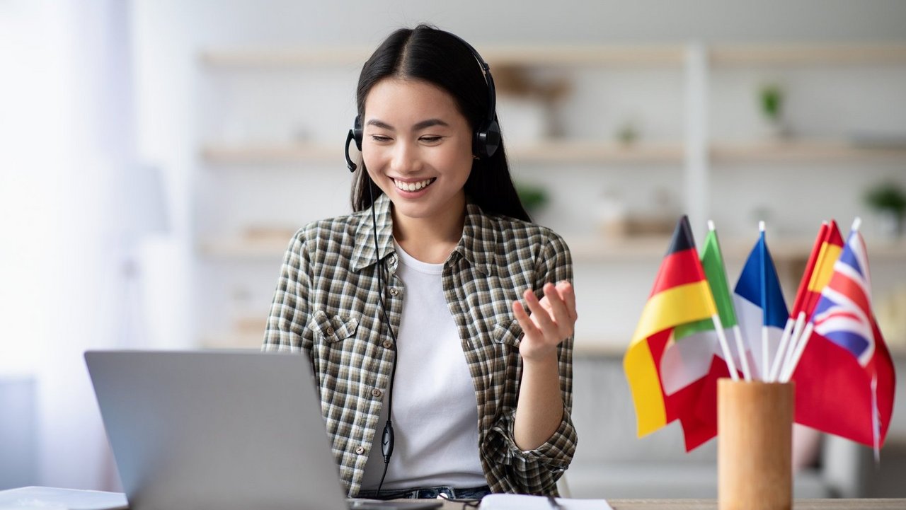 Happy asian lady using laptop and headset, learning foreign language