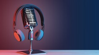 Podcasting and radio concept with retro microphone and headphones on empty wooden table and dark blank wall background with place for your logo or text. 3D rendering, mock up