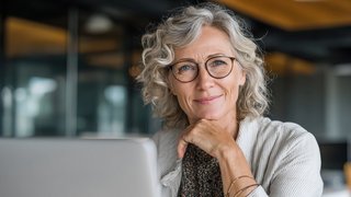 Ältere Mitarbeitende. Eine ältere Mitarbeiterin sitzt vor einem Laptop.