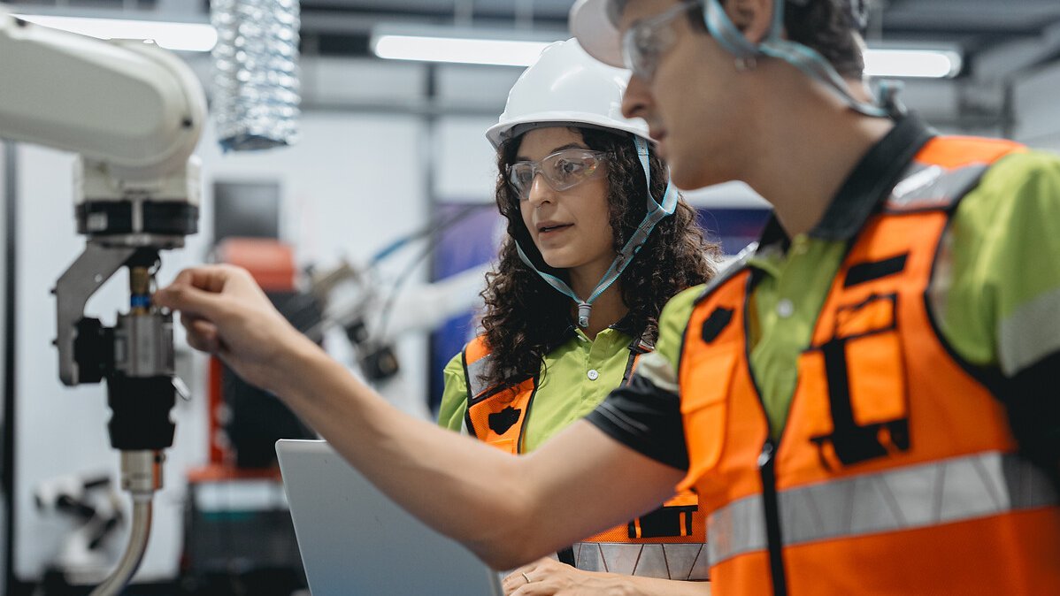 Smart Latino woman and male colleague working on AI technology in robotic electronic engineering laboratory. Hispanic engineer technician team research in robot machine futuristic automated control.